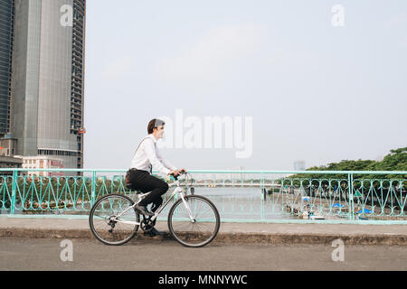 Überall von seinem Fahrrad. Seitenansicht der junge Unternehmer freuen uns auf dem Fahrrad Stockfoto