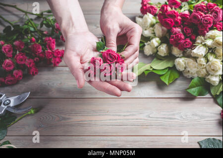 Florist bei der Arbeit. Weibliche Hände sammeln eine Hochzeit Strauß Rosen. Die Menschen in den Prozess der Arbeit Stockfoto