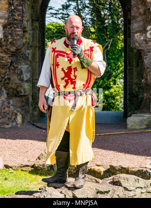 Dirleton, East Lothian, Schottland, UK, 19. Mai 2018. Dirleton, East Lothian, Schottland, UK, 19. Mai 2018. Dirleton Castle Angriff Re-enactment. Die historische Saltire Society staging a tongue-in-cheek Re-enactment eines Angriffs von Robert the Bruce, König von Schottland, um 1311, das Schloss aus dem Englischen, in authentischer Kleidung und Rüstung gekleidet und schwingende replica Waffen im historischen Umfeld Schottland Dirleton Castle. Ein Mann spielt Robert Bruce gekleidet im Kostüm mit einem Löwen. Stockfoto