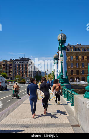 Surfer mit ihren Surfbrettern Kreuzung Kursaal Brücke in San Sebastian an der sonnigen Tag. Donostia, San Sebastian, Guipuzcoa, Baskenland, Spanien. Stockfoto