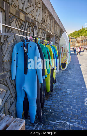 Neoprenanzüge und Surfboards s Shop in La Zurriola Strand mit Monte Urgull im Hintergrund. San Sebastian. Baskenland Guipuzcoa. Spanien. Stockfoto