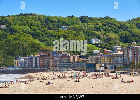 Die Menschen genießen Sie ein Sonnenbad in La Zurriola Strand mit Monte Ulia im Hintergrund. San Sebastian. Baskenland Guipuzcoa. Spanien. Stockfoto