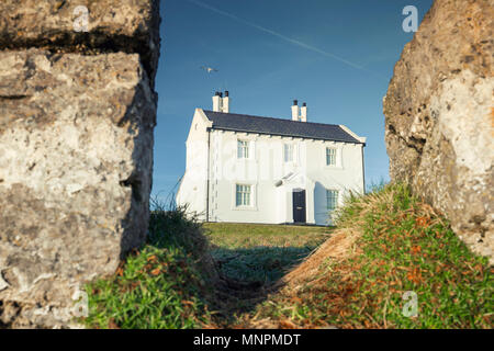 Historische Küsten weiße Haus sehen Sie durch alte erodiert Klippen von Penmon Strand in Nord Wales, Großbritannien Stockfoto