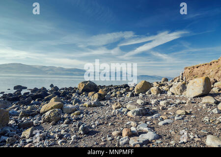Felsigen Ufer Menai Strait mit spektakulärem Blick auf die Berge von Snowdonia. Insel Anglesey im Norden von Wales. Großbritannien Stockfoto