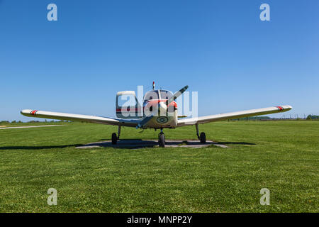 Das Flugzeug Piper Cherokee steht auf dem grünen Rasen an einem sonnigen Tag. Einen kleinen privaten Flugplatz mit unterschiedlichen Ebenen. Private Aviation Stockfoto