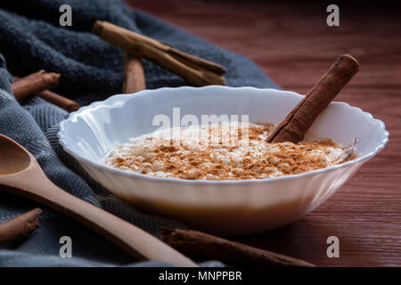 Nahaufnahme der weiße Schüssel mit cremiger Milchreis mit Zimt auf Stoff serviert geerdet Stockfoto