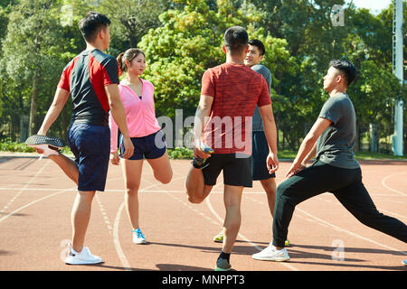 Vier asiatische junge Erwachsene Aufwärmen stretching Beine auf Schiene. Stockfoto