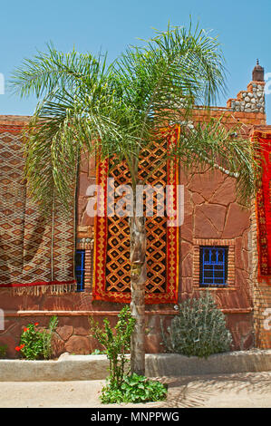 Eine Anzeige der bunten Teppich traditioal dekoriert in einem traditionellen Gebäude mit Palm Tree Stockfoto