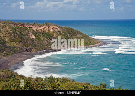 Eine tropische Karibik Strand mit schwarzem Sand und Meer Wellen am Ufer Stockfoto