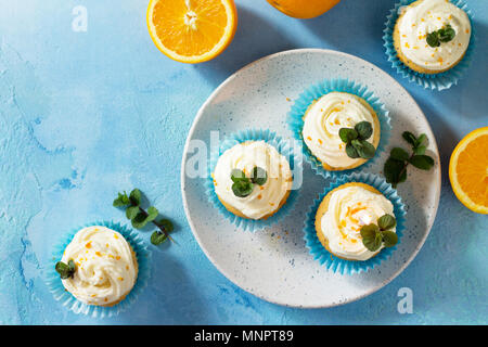 Bunte orange Cupcake mit Geburtstag Kerze auf einem blauen Stein oder Schiefer Hintergrund. Stockfoto