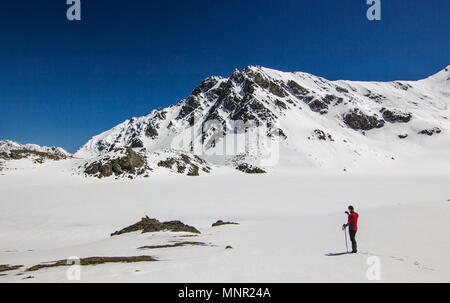 Mann stand auf Schnee in den Bergen bei Tageslicht Stockfoto