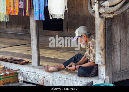 BENA, Indonesien - 19. Mai: Ein unbekannter Mann Sands eine kleine Schüssel in der vor einem Haus am 19. Mai 2017 in dem traditionellen Dorf von Bena, Indonesien. Stockfoto