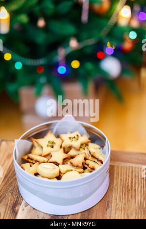 Frisch gebackene hausgemachte Cookies in einer Blechdose in der Nähe Weihnachtsbaum dekoriert Stockfoto