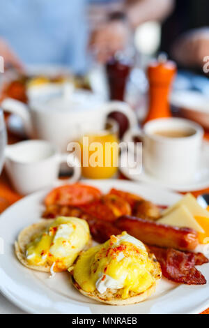 Köstliches Frühstück mit Eggs Benedict, Speck, Orangensaft und Kaffee Stockfoto