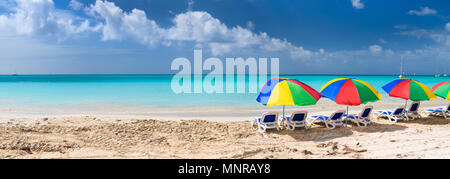 Panorama von Stühlen und bunte Sonnenschirme auf einem wunderschönen tropischen Strand in der Karibik Stockfoto