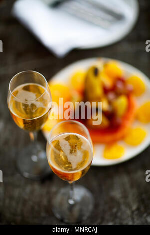 Zwei Gläser mit Champagner und Obst auf Holz vintage Fach für besondere Anlässe oder Feier serviert. Stockfoto