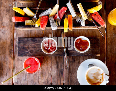 Blick von oben auf die leckeren Bio essen zum Frühstück auf rustikalen Holztisch. Kaffee, Obst, Saft und Marmelade flach. Stockfoto