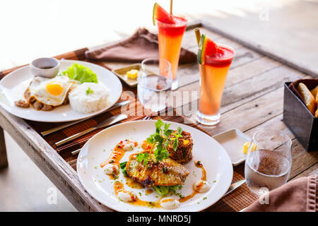 Ein leckeres Mittagessen für zwei im Restaurant Fisch, Reis, Spiegelei und grünes Gemüse Stockfoto