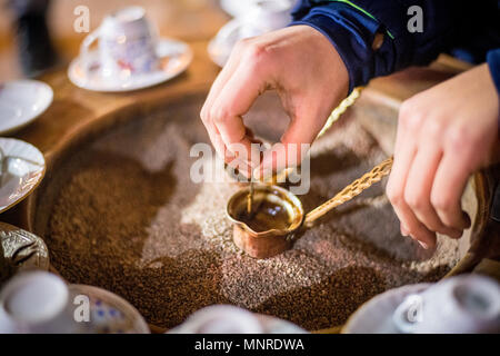 Nahaufnahme auf Händen die Zubereitung von türkischem Kaffee in Kupfer cezve Topf, Istanbul, Türkei Stockfoto