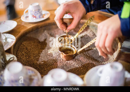 Nahaufnahme auf Händen die Zubereitung von türkischem Kaffee in Kupfer cezve Topf, Istanbul, Türkei Stockfoto