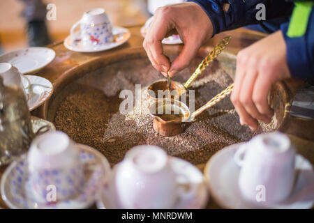 Nahaufnahme auf Händen die Zubereitung von türkischem Kaffee in Kupfer cezve Topf, Istanbul, Türkei Stockfoto