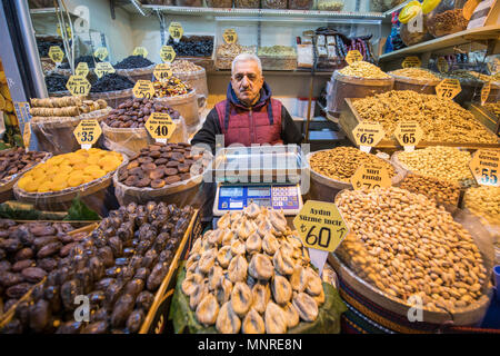 Erwachsene männliche shop Kaufmann steht hinter der Theke, die Körbe voll getrocknete Früchte und Nüsse zum Verkauf in Istanbul, Spice Bazaar in der Türkei Stockfoto