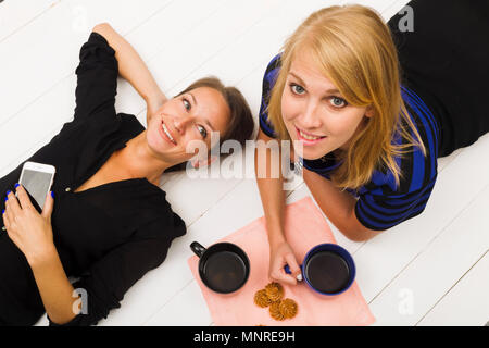 Zwei Mädchen auf weißem Holz- Hintergrund, Ansicht von oben, Studio, Beleuchtung Stockfoto