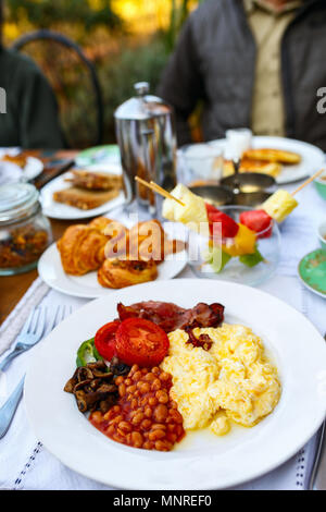 Köstliches Frühstück mit Rührei, Bohnen, Speck und Gemüse Stockfoto