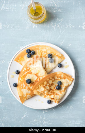 Pfannkuchen mit Heidelbeeren und Honig. Hausgemachte Pfannkuchen, Crepes auf blauen Tabelle, kopieren. Stockfoto