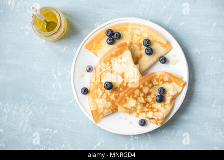 Pfannkuchen mit Heidelbeeren und Honig. Hausgemachte Pfannkuchen, Crepes auf blauen Tabelle, kopieren. Stockfoto