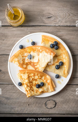 Pfannkuchen mit Heidelbeeren und Honig. Hausgemachte Pfannkuchen, Crepes auf Holztisch, kopieren. Stockfoto