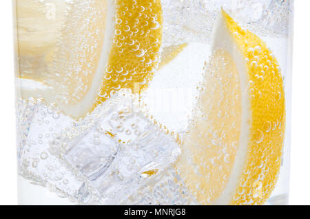 In ein Glas mit Eiswürfeln von schmelzendem Eis Scheiben eine saftige Zitrone. Stockfoto