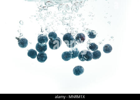 Heidelbeeren in das Wasser sinken mit Luftblasen weißer Hintergrund Stockfoto