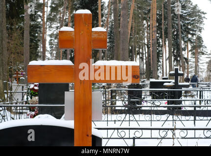 Holzkreuz und künstliche Blumen auf dem Grab eines orthodoxen Friedhof im Winter Stockfoto