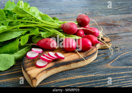 Sommer geernteten roten Rettich. Wachsende Bio Gemüse. Große Haufen rohe Frische saftige Garten Rettich auf dunklen Boards bereit zu essen. Stockfoto