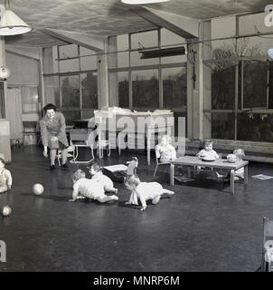 1948, historische Bild zeigt das Innere einer Nachkriegszeit Baumschule mit Kindern spielen und Lehrerin, England, UK. Stockfoto