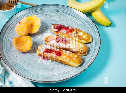 Quark Pfannkuchen mit Hafer, syrniki und Pfirsich auf blauem Hintergrund. Stockfoto