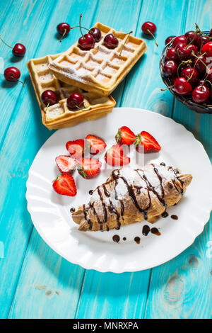 Frühstück: Waffeln und Croissant mit Kirschen und Erdbeeren. Stockfoto