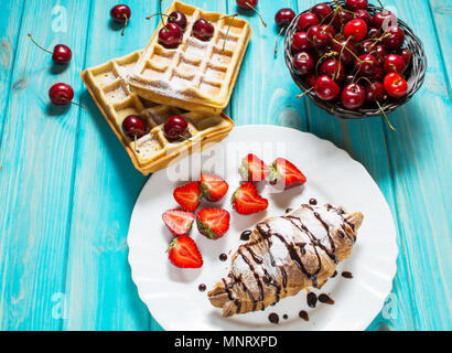 Frühstück: Waffeln und Croissant mit Kirschen und Erdbeeren. Stockfoto
