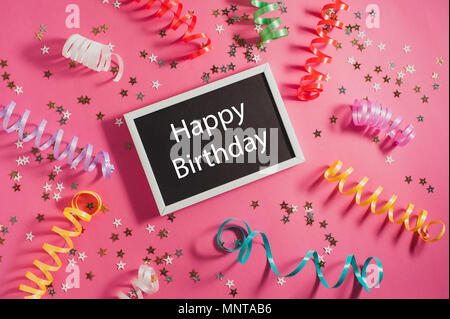 Bunte party Luftschlangen, Gold kleine Sterne und Blackboard mit Text Happy Birthday auf Rosa backgrond. Stockfoto