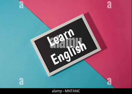 Englisch lernen - Text auf schwarzen Brettes auf Blau und Rosa hellen Hintergrund. Stockfoto