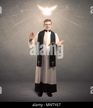 Ein heiliger Priester lesen ein Gebet aus der Bibel mit bebilderter Leuchtende Engel über seinem Kopf Konzept. Stockfoto