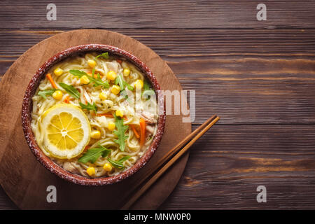 Asiatische Küche chinesische Suppe mit Nudeln in der Schüssel Gemüse Zwiebel Karotten grünen Blätter Rucola Mais- und Hühnerfleisch Stäbchen Wabi Sabi style Low Key Stockfoto