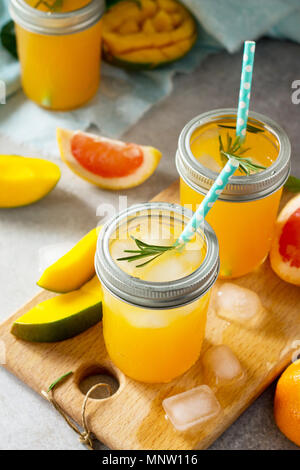 Erfrischende Sommercocktails aus Zitrusfrüchten und Mango, kalten Drink oder einen Drink mit Eis auf einem schwarzen Hintergrund. Konzept der vegetarischen Essen, frische Vitamine Stockfoto