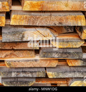 Stapel gestapelt Bauholz. Getrocknete Holz Bretter mit einem Knacken. Verschiedene Arten von Holz. Platz. Getönt. Close-up. Stockfoto