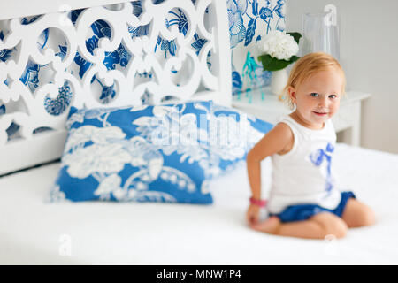 Portrait von adorable lächelnd Kleinkind Mädchen sitzt auf dem Bett, schön eingerichtete Schlafzimmer Stockfoto