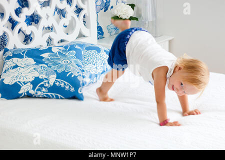 Portrait von liebenswert verspielten Kleinkind Mädchen springen auf Bett in schön eingerichtete Schlafzimmer Stockfoto