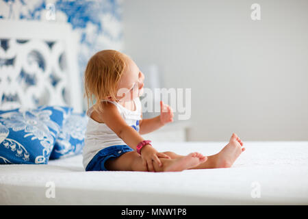 Portrait von verspielten Kleinkind Mädchen sitzt auf dem Bett, schön eingerichtete Schlafzimmer Stockfoto