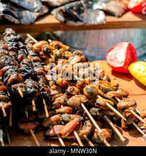 Leckere Spieße mit Muscheln, aufgereiht auf Holzstäbchen. Köstliche Meeresfrüchte auf einer hölzernen Hintergrund. Platz. Close-up. Stockfoto