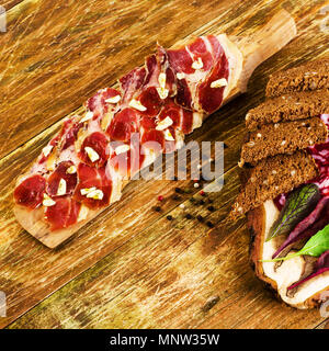 Schneidbrett, Brot, Speck und Knoblauch auf einer hölzernen Hintergrund. Ansicht von oben. Platz. Close-up. Stockfoto